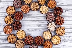 an arrangement of nuts arranged in the shape of a wreath on a white wooden background