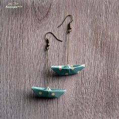 two small boats are hanging from hooks on a wooden surface, one is blue and the other is white with polka dots