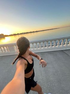 a woman is running on the sidewalk by the water