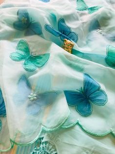 a blue and green butterfly print fabric with lace trim on the bottom half of it