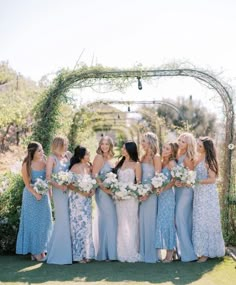 a group of women standing next to each other in front of a pergol arch