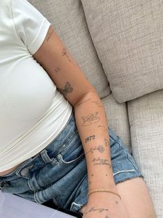 a woman with tattoos on her arm sitting on a couch