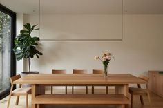 a wooden table and bench in front of a large window with potted plant next to it