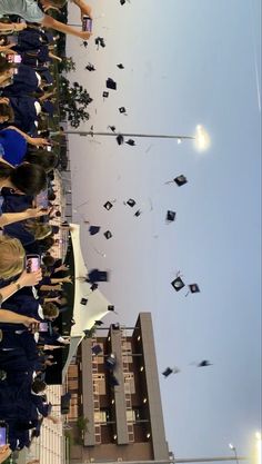 a group of people standing next to each other in front of tall buildings with graduation caps on them