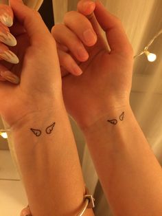 two women with matching tattoos on their arms holding onto one another's wrist and the other