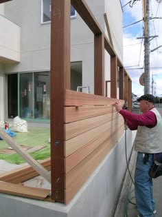 a man that is standing next to a building with wood siding on it's side