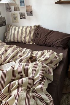 an unmade bed with brown and white striped comforter on it's side