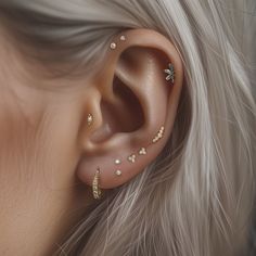 a close up of a person's ear with gold and diamond studs on it