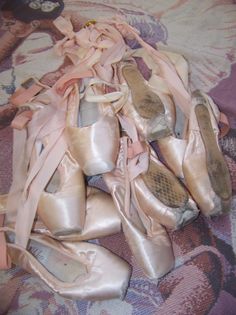 a pile of ballet shoes on top of a bed