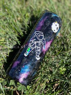 an empty spaceman bottle is sitting in the grass with its lid up and it's painted