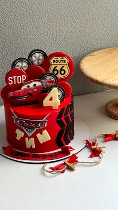 a red cake with cars on it sitting on top of a table