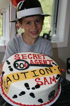 a young boy wearing a hat and holding a cake with the name caution sam on it