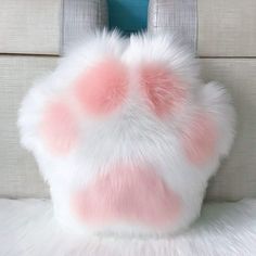 a pink and white fur bag sitting on top of a couch