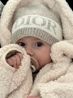 a baby wrapped in a blanket and drinking from a cup