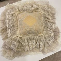 a decorative pillow with ruffles and lace on it sitting on top of a table