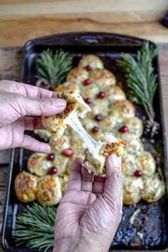 a person holding a piece of food in front of a tray with other food on it