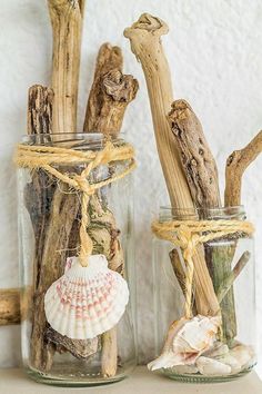 two glass jars with seashells and driftwood in them