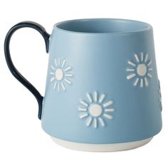 a blue and white coffee mug with sunflowers on the side, sitting in front of a white background