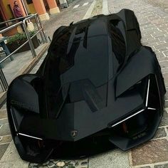 a black sports car parked on the side of a road next to a brick sidewalk