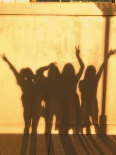 the shadow of three people holding their hands up