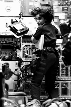 a woman is standing in front of many electronic equipment