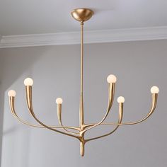 a gold chandelier hanging from the ceiling in a room with gray walls and white trim