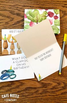 some cards and pens sitting on top of a wooden table with greetings for someone's birthday