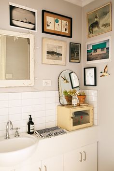 a bathroom with pictures on the wall and a sink in front of it is shown