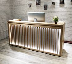 a wooden desk with a computer on top of it in an empty room next to a white brick wall