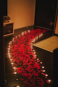 the floor is decorated with red petals and lit candles in the shape of a heart