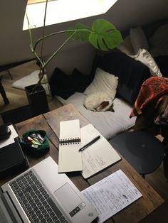 an open laptop computer sitting on top of a wooden table next to a notebook and pen