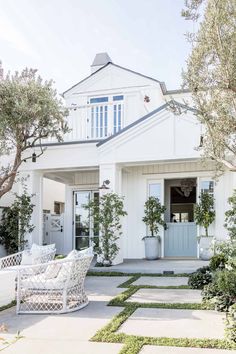 a white house with blue shutters and potted plants on the front porch area