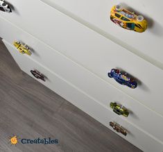 a white dresser with toy cars on the drawers