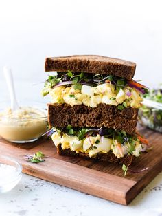 a sandwich is stacked on top of a cutting board with other food in the background