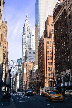 a city street lined with tall buildings and cars driving down it's side walk