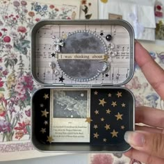 an open tin box with some pictures inside it and writing on the side in gold stars