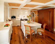 a large kitchen with white cabinets and wooden flooring, along with a breakfast nook