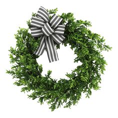 a black and white bow on top of a green wreath with greenery around it