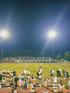 the band is on the sidelines at night in front of an empty football field