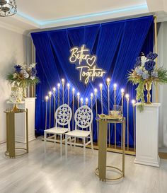 a blue stage set with white chairs and candles