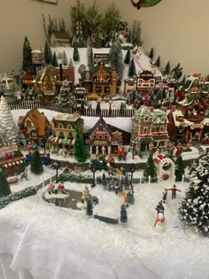 a christmas village is shown in the middle of a white sheeted tablecloth with snow on it