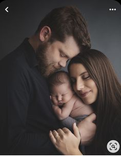 a man and woman holding a baby in their arms