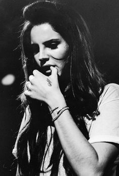 black and white photograph of a woman holding her hands to her mouth while standing in front of a microphone