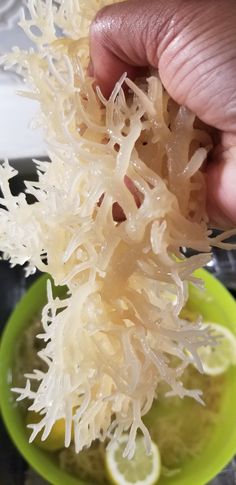 a person is picking up shredded cheese from a green bowl with limes in it