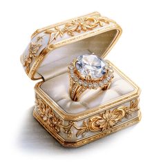 an ornately decorated ring box with a white diamond in the center and gold trimmings