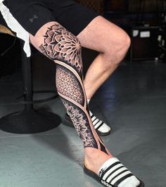 a man sitting on top of a wooden bench wearing black and white shoes with tattoos