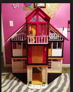 a doll house is shown on the floor in front of a pink wall and zebra print rug