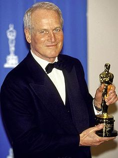 an older man in a tuxedo holding up his oscar award