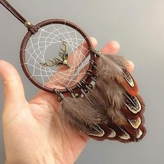 a hand holding a brown and white dream catcher