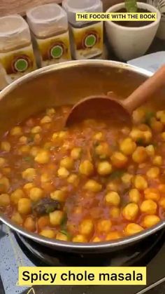 a pan filled with chickpeas and sauce on top of a stove next to jars